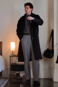 A man in a dark outfit taking a picture with a camera.